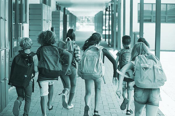 School kids running in elementary school hallway, back view